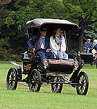 A Curved Dash Oldsmobile, produced in 1901, drives into a Lansing, Mich., park in 1997 as part of the automaker`s 100th anniversary.  Photo by Dale Atkins, Associated Press.